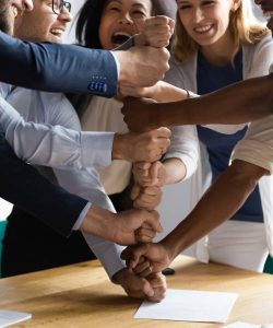 Group of Business professionals placing hand one above another which indicated teamwork
