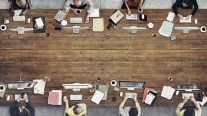 Top view of a group of business people working at a table with desktop coffee papers